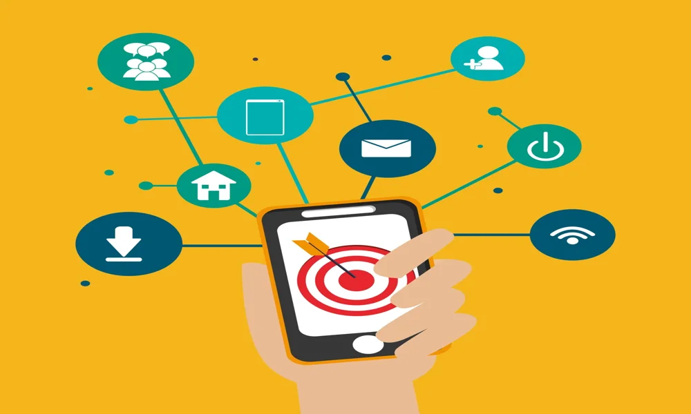 Ruka držící mobilní telefon s grafickými ikonami kolem něj.